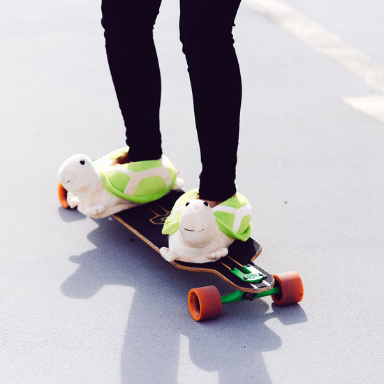 Person auf Skateboard trägt Schildkröten Hausschuhe