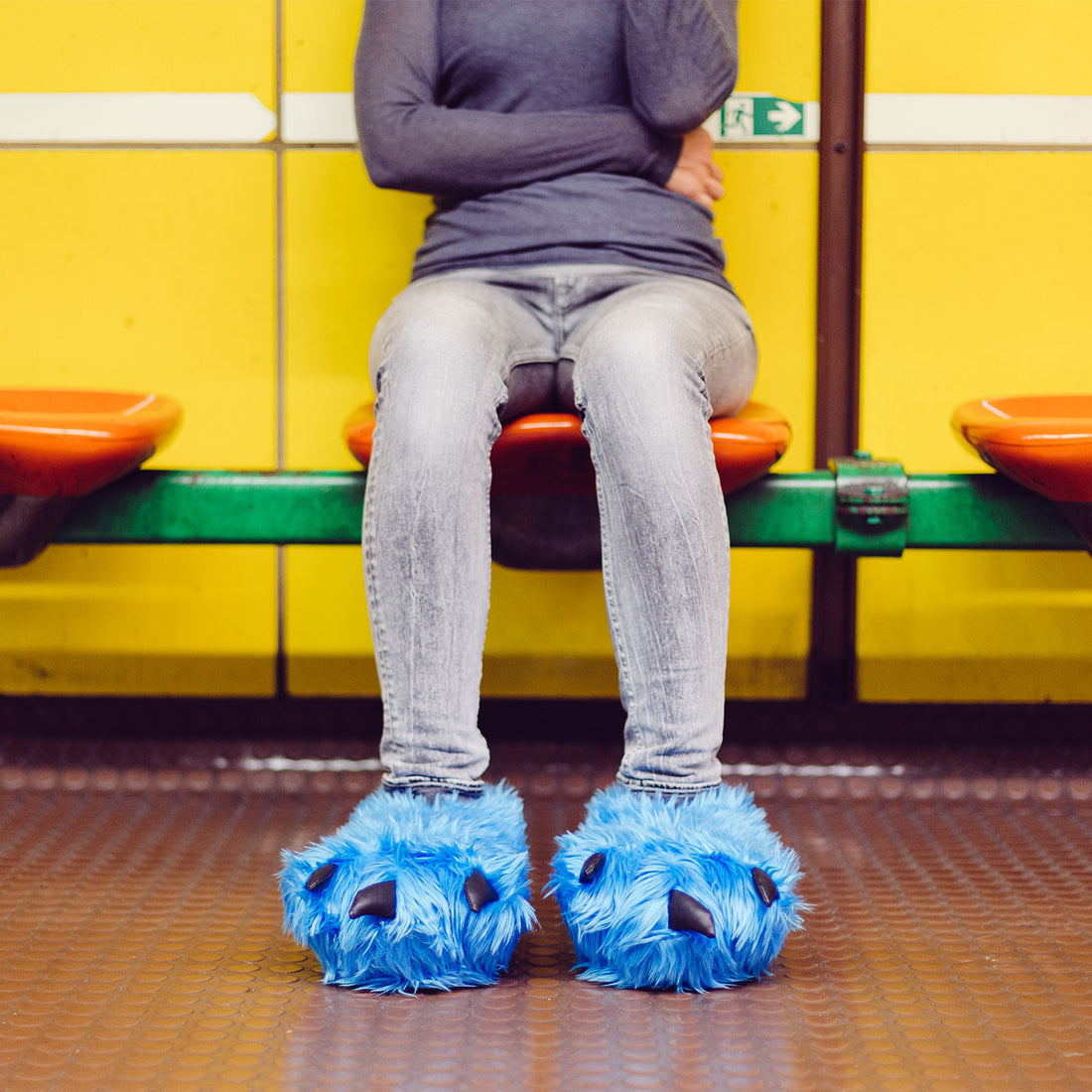 person sittting on bank wearing blue claw slippers